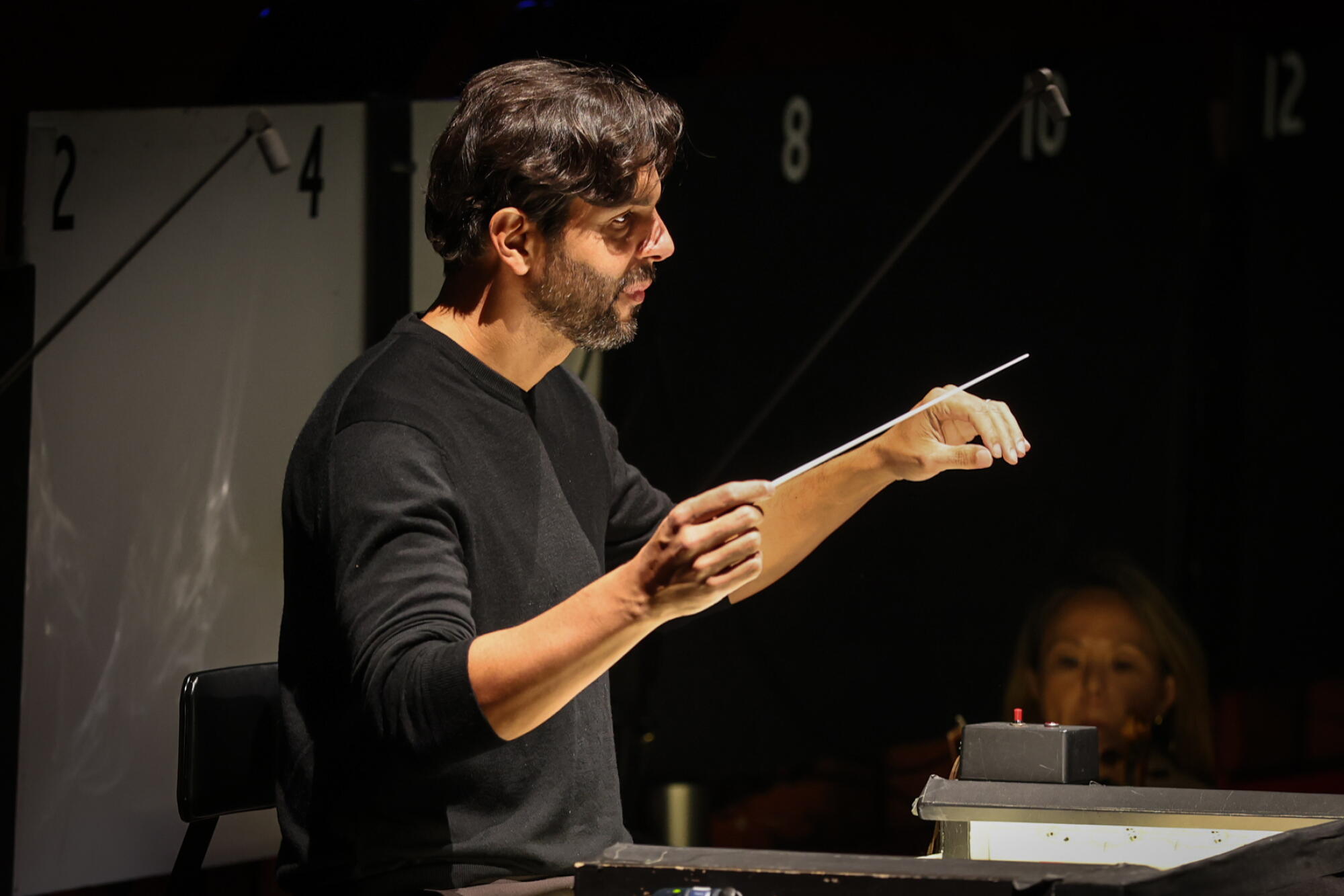 A man conducts an orchestra on stage.