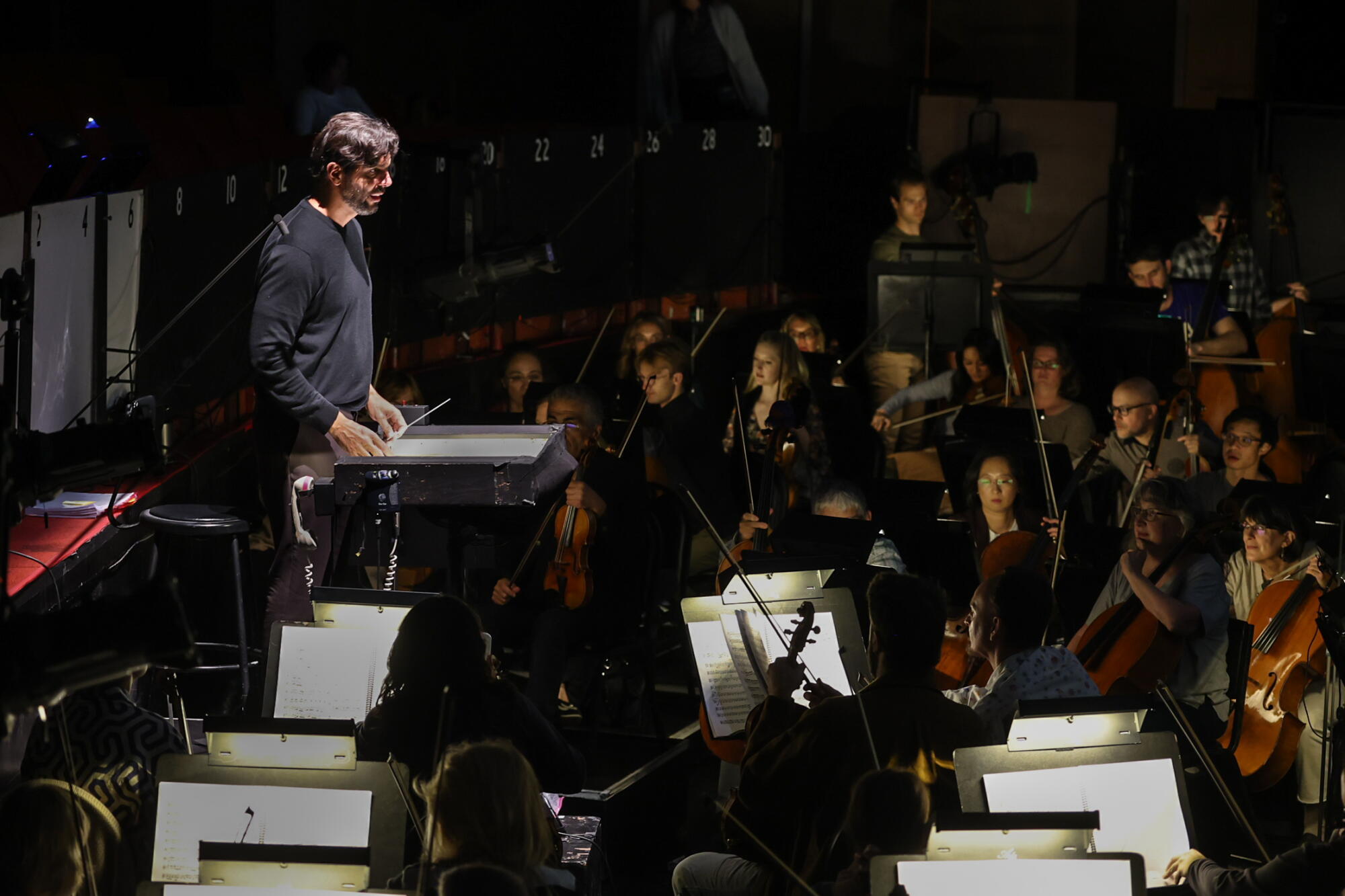 A man conducts and orchestra from the podium.