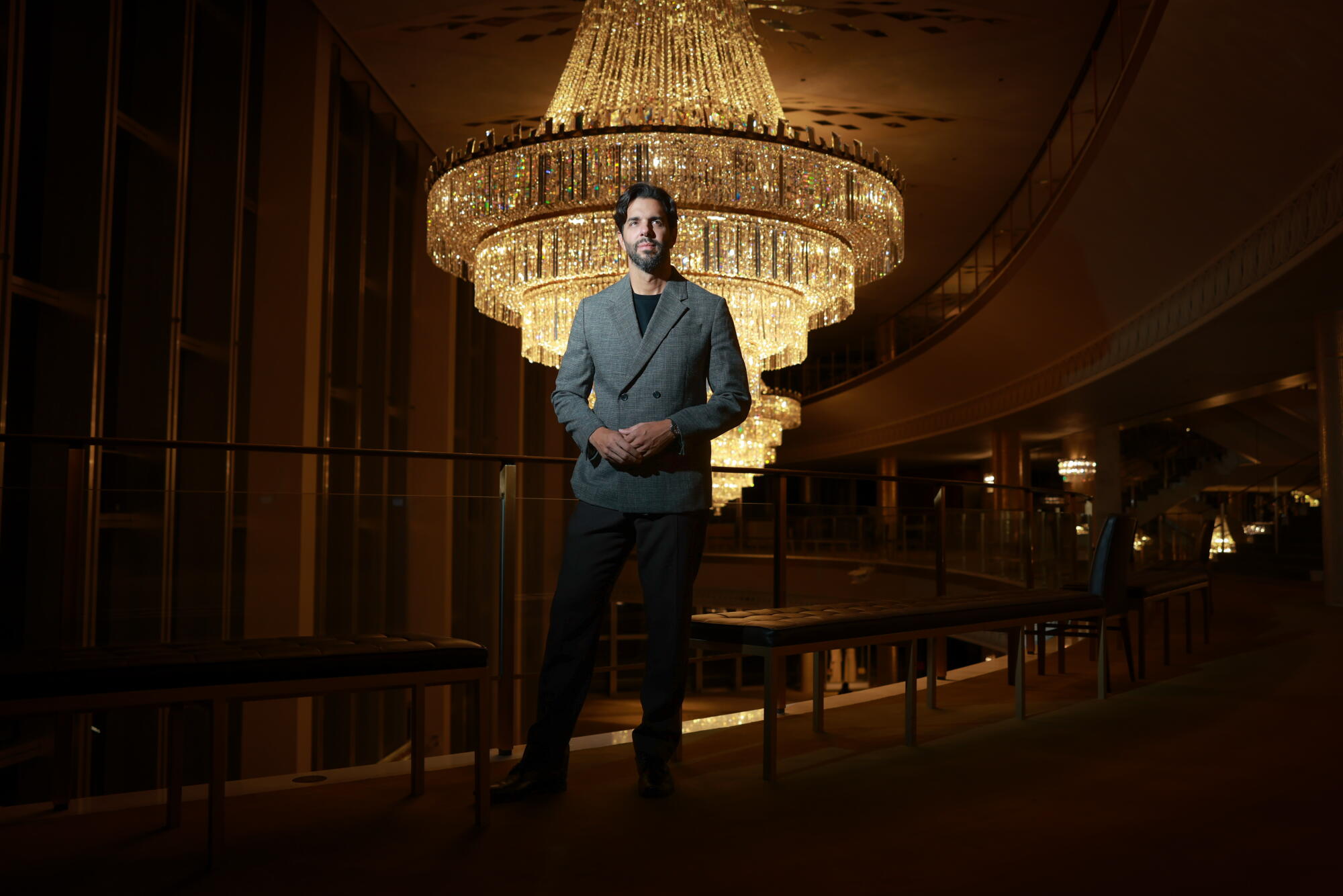 A man stands in front of a large chandelier.