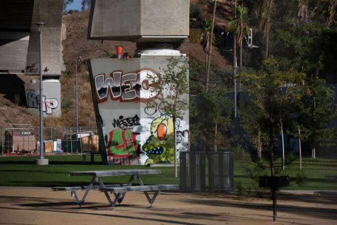 Graffiti is seen on a pilar of a bridge in a bridge.