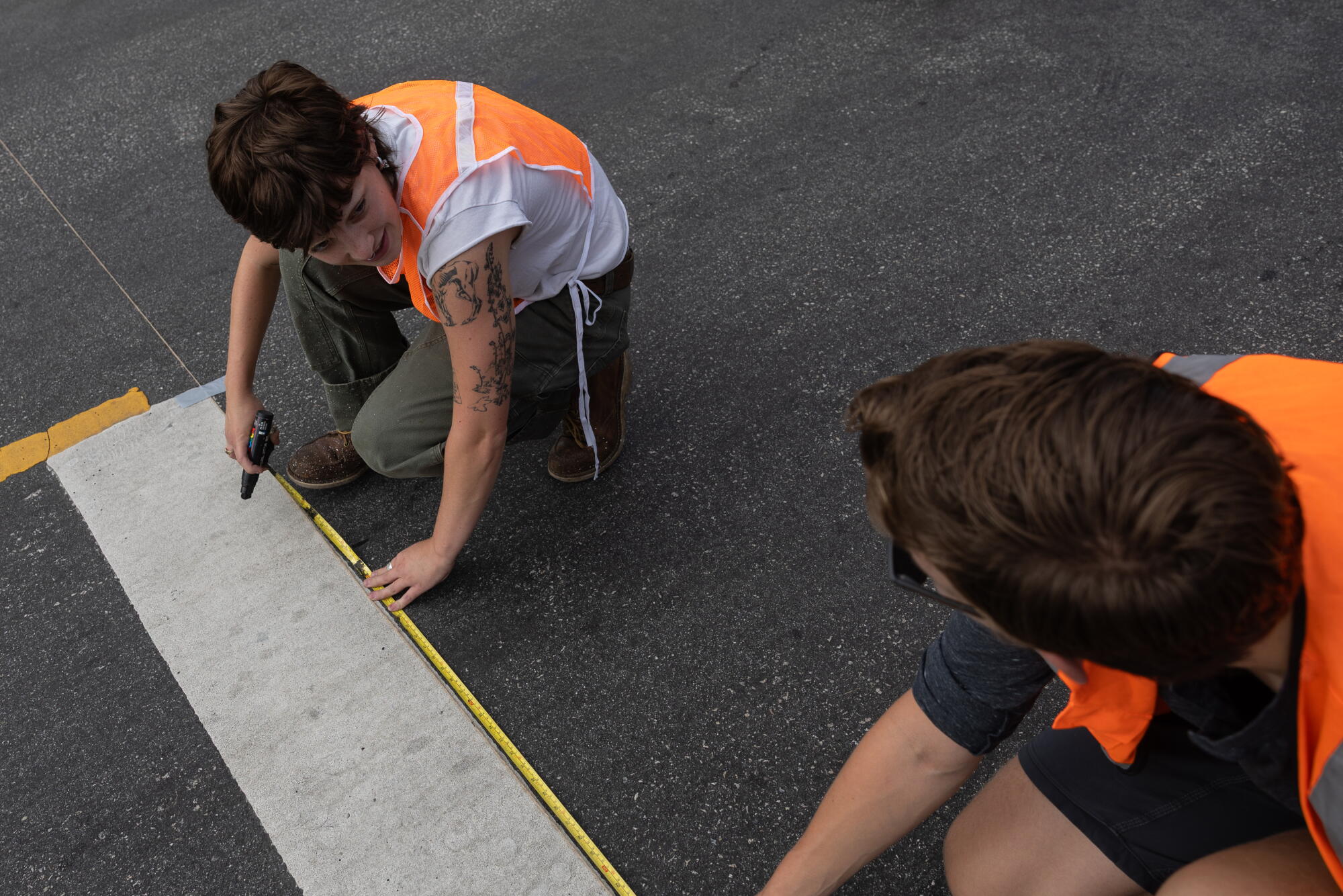 Venus, a volunteer, measures the spacing between the lines of a crosswalk.
