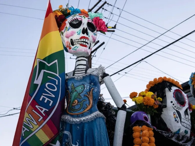 A low angle view of a large catrina structure with a Pride flag.