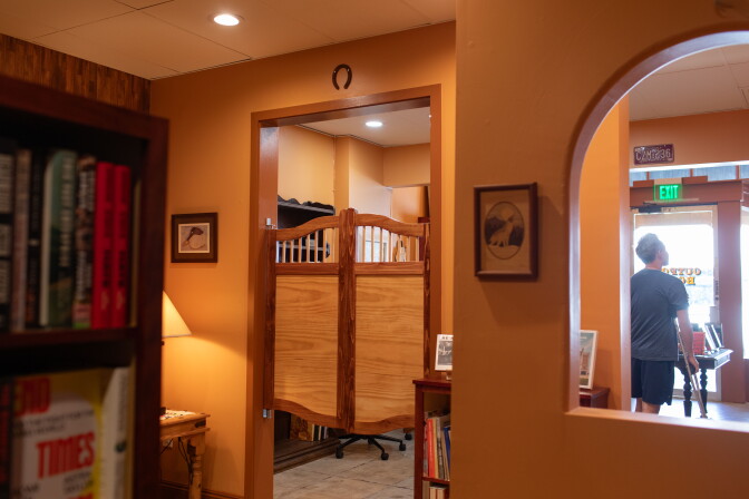 Wooden corral doors in a doorway next to a curved window inside a shop.