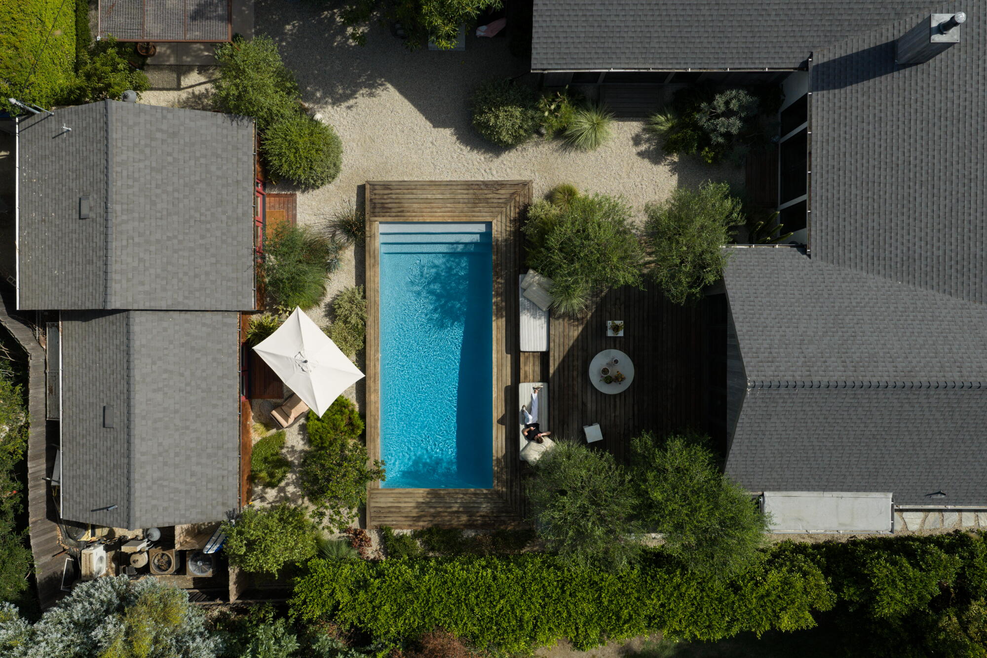 An aerial view of a person lying on a couch outside the family's pool and ADU.