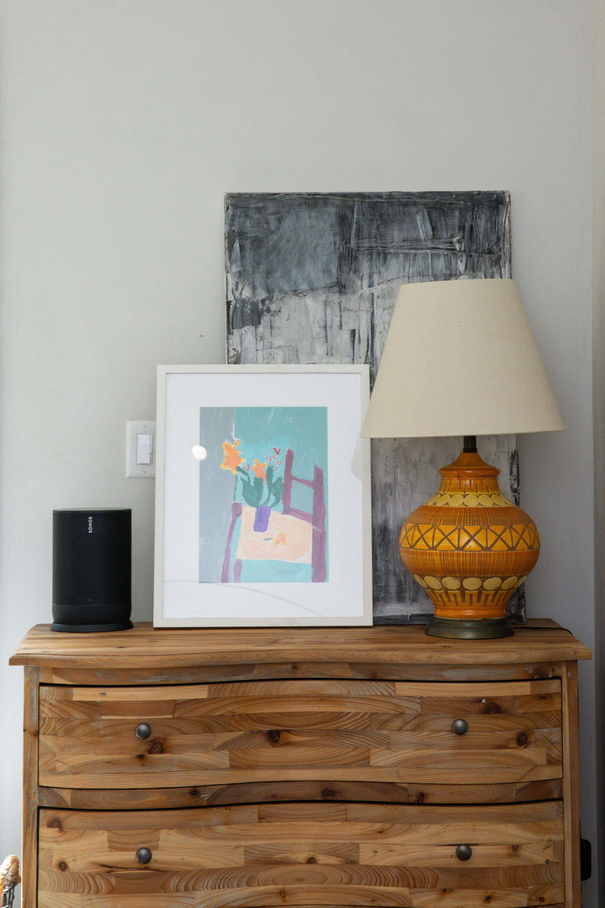 In the living room, a vintage lamp and artworks rest on a dresser. 