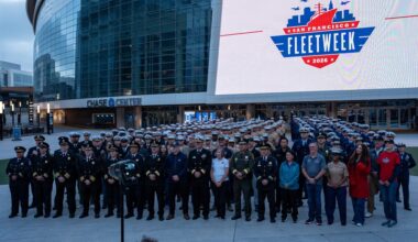 U.S. Sailors, Marines and Coast Guardsmen pose with Fleet Week organizers for a photo during San Francisco Fleet Week