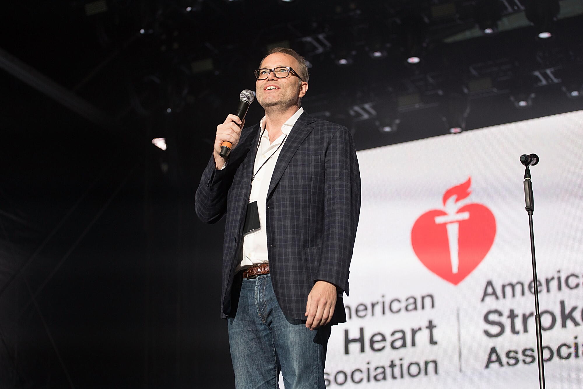 Hil Davis speaking into a mic onstage during an event