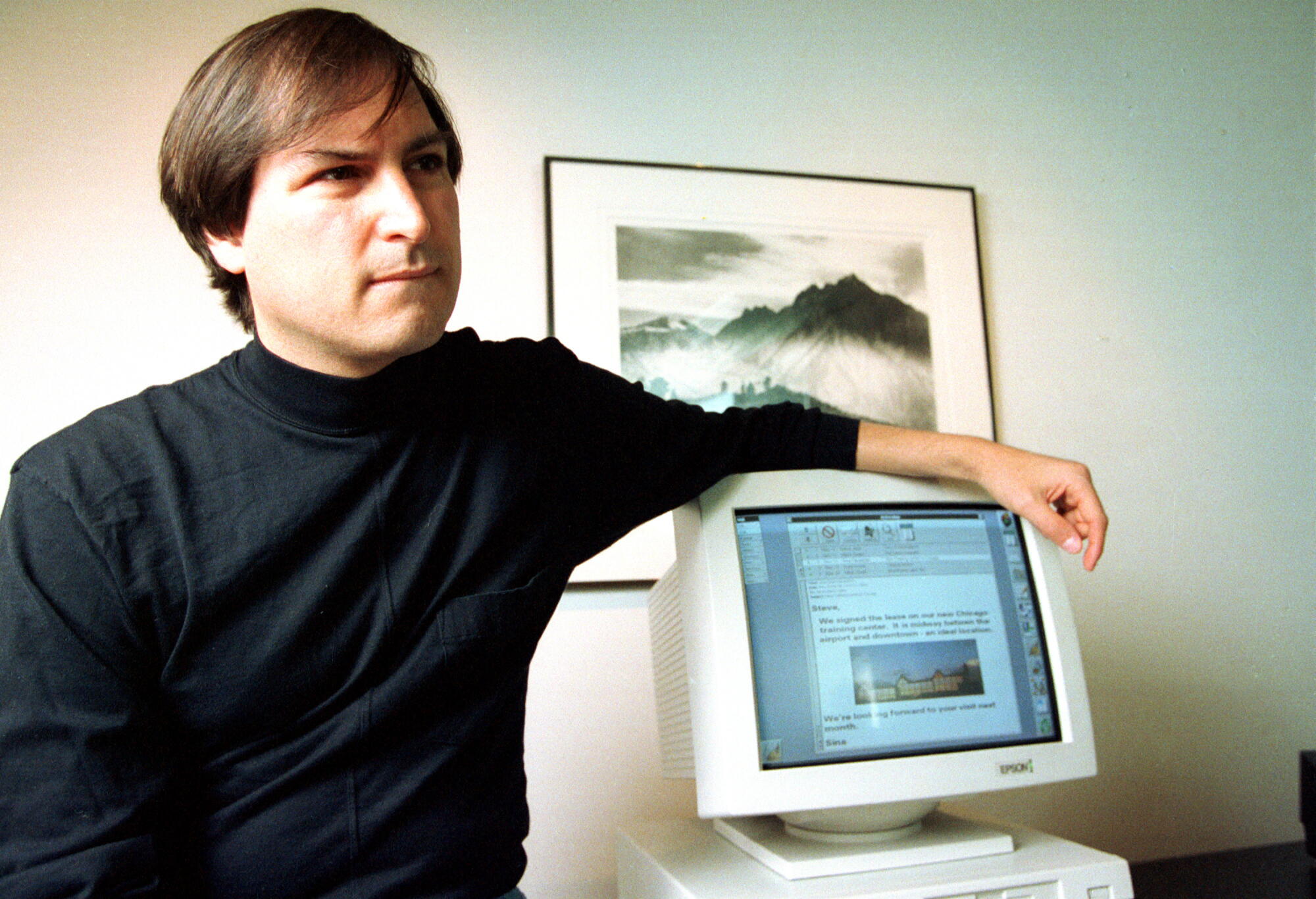 Apple co-founder Steve Jobs resting an arm atop a CRT computer monitor in 1993