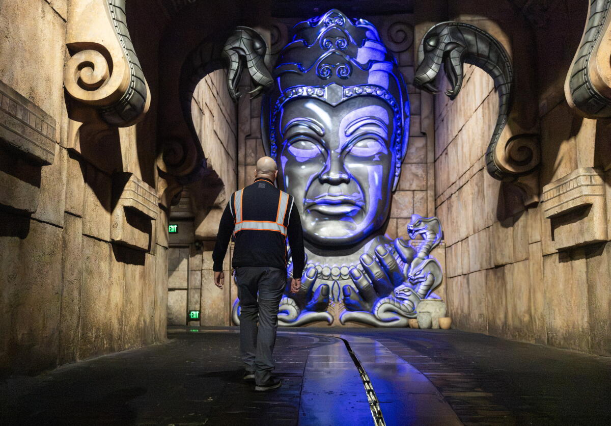 A man in front of a large face monument.