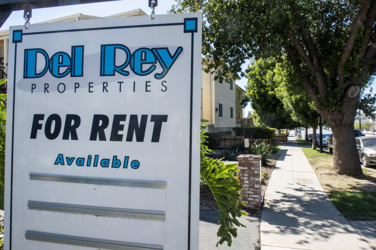A sign says "Del Rey Properties, for rent, available" next to a sidewalk.