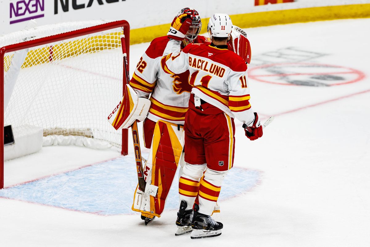 Mikael Backlund #11 of the Calgary Flames celebrates a win with Dustin Wolf #32 of the Calgary Flames after an NHL game against the Anaheim Ducks on October 13, 2026 at Honda Center in Anaheim, California.