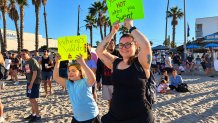 Dani Maloney and her daughter, Lilli, 10, hold signs of support to cheer runners in Saturday's 5K, October  3, 2026.