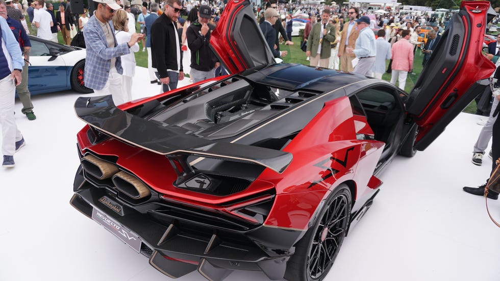 A sleek red Lamborghini Revuelto SV with doors open, showcasing its engine and design at an automotive event.