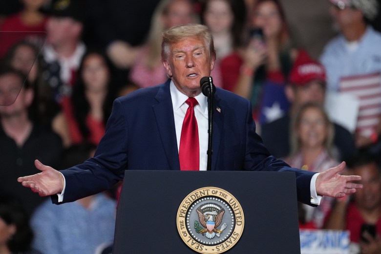 President Donald Trump at a podium with a crowd visible behind him.
