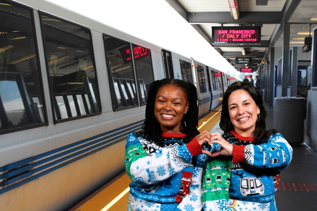 Models wearing BART Holiday sweater and BART station