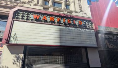 A closed storefront with a blank marquee sign above showing the word "WARFIELD" in orange letters on a decorative facade.