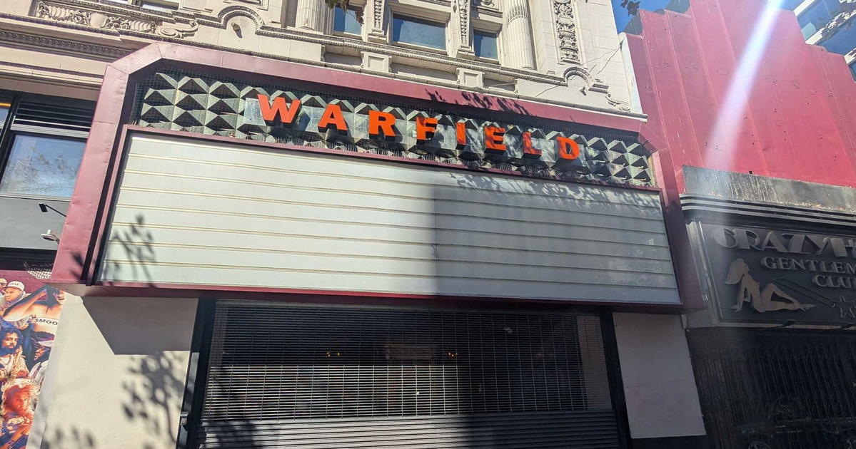 A closed storefront with a blank marquee sign above showing the word "WARFIELD" in orange letters on a decorative facade.