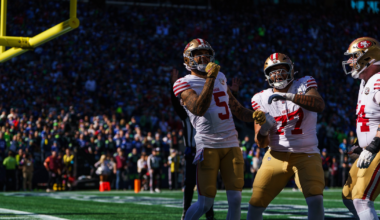 Three San Francisco 49ers football players celebrate in the end zone under the goalpost during a game with a crowd in the background.