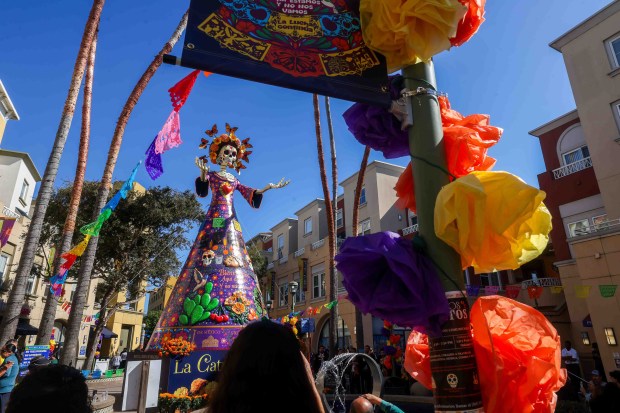 Visitors take photos and video of La Catrina, a monumental 34-foot sculpture handcrafted in Mexico City, installed in the heart of the Fruitvale district in Oakland, Calif., on Thursday, Oct. 1, 2026. According to The Unity Council, the traditional Mexican art piece is the tallest Catrina sculpture in the United States, honoring culture, pride, remembrance, resilience, and generations of immigrants who empower and enrich the city. The ceremony featured speakers including Mayor Barbara Lee, Councilmember Noel Gallo, Consul General of Mexico in San Francisco Marco Antonio Mena Rodriguez, Unity Council President Chris Iglesias, and Visit Oakland President Peter Gamez, along with dance performances and live mariachi music. The sculpture will be on display through the annual Día de los Muertos festival. (Ray Chavez/Bay Area News Group)