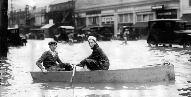 Oakland, CA November 26, 1926 - Two boys put a boat on Grand Avenue to get around town after a terrific downpour flooded basements and suspended traffic. Lake Merritt frequently flooded during heavy rains before the installment of a flood control station in the 1960s. (Oakland Tribune Photo)