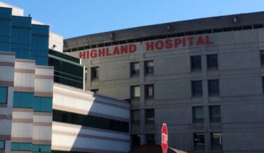 A hospital with its name "Highland Hospital" hanged on the top of the building.