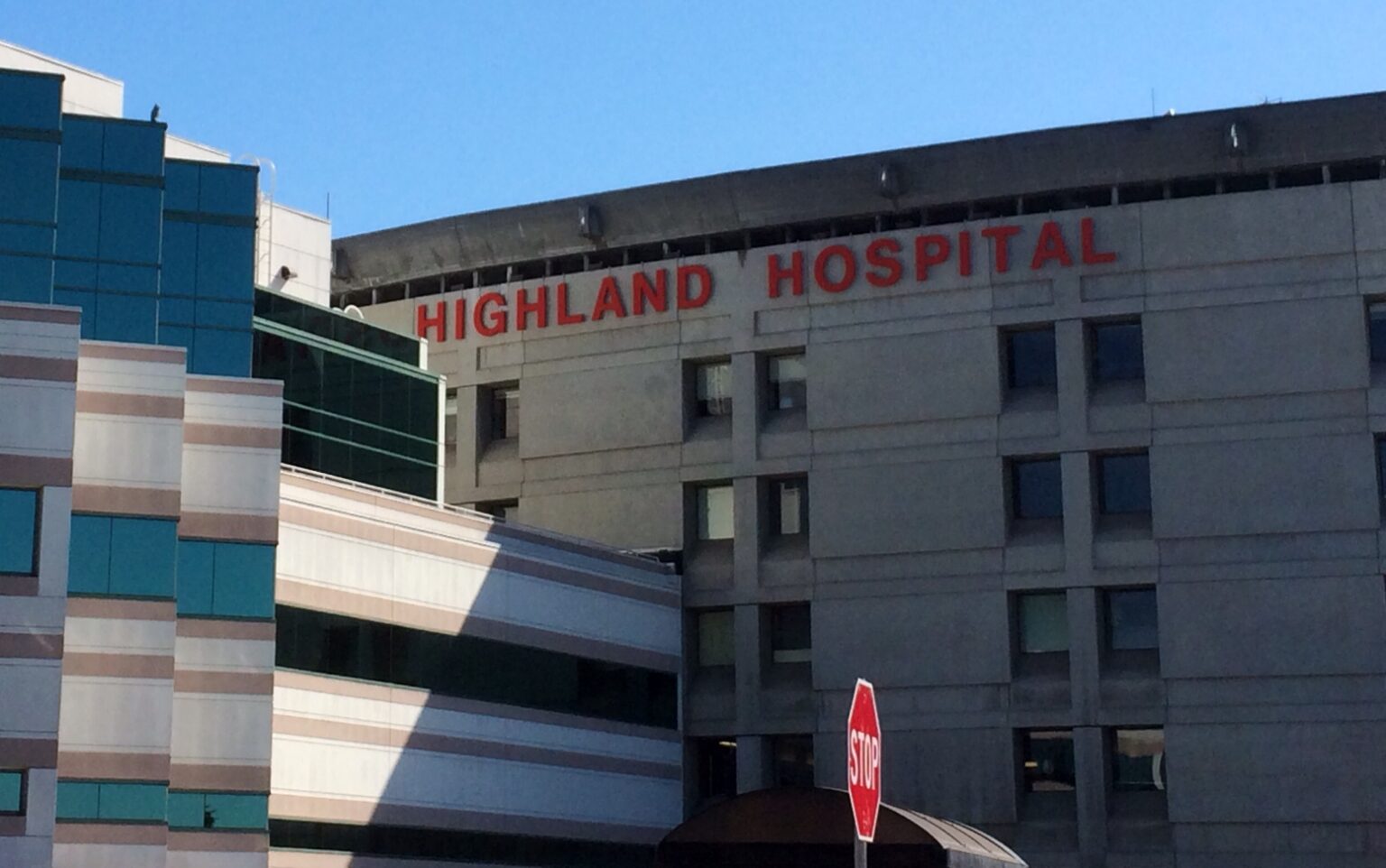 A hospital with its name "Highland Hospital" hanged on the top of the building.