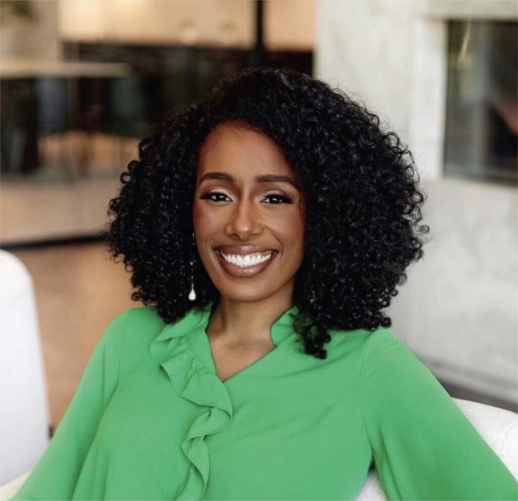 Headshot of psychology reseacher Jasmin Brooks Stehpens sitting on a white couch wearing a bright green blouse and smiling at the camera.