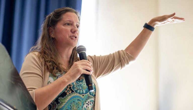 a woman holding a microphone gesturing as she speaks
