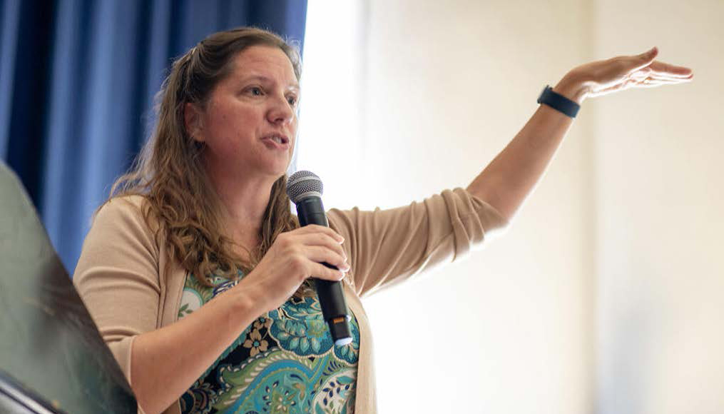 a woman holding a microphone gesturing as she speaks