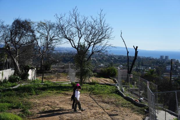 FILE - Starr Parodi, in pink hat, and her daughter, Isolde Fair, walk on their fire-ravaged property on the one-year anniversary of the Palisades Fire in the Pacific Palisades neighborhood of Los Angeles, Jan. 7, 2026. (AP Photo/Jae C. Hong, File)