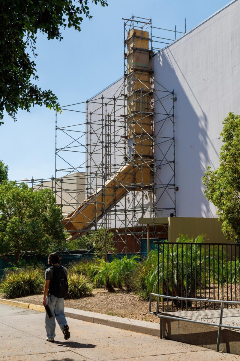 A person walks in front of chute wrapped in scaffolding
