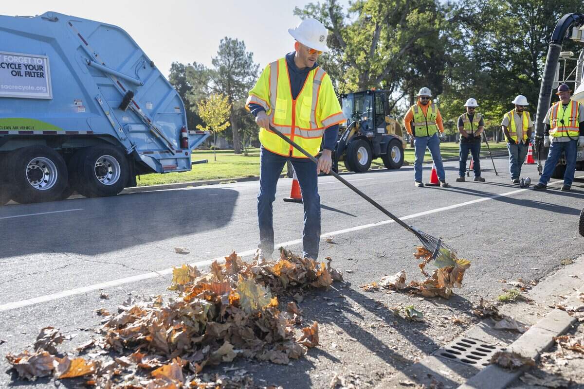 Sacramento Mayor Kevin McCarty clears leaves from a drain during a winter weather preparation event in Land Park on Monday.