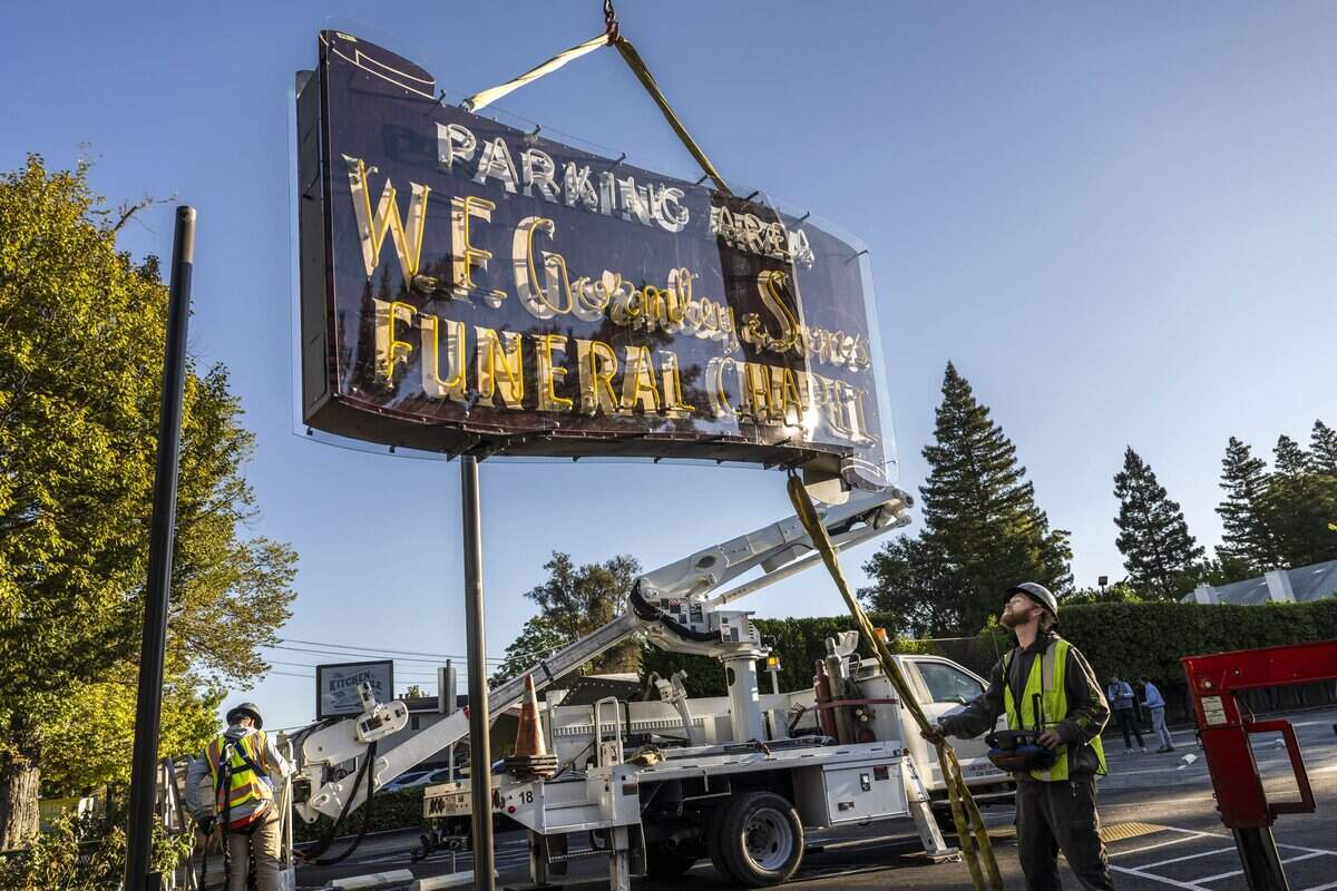 Hank Uroff guides the restored W.F. Gormley Funeral Chapel sign as it is installed by the Pacific Neon Company at its new location on Riverside Boulevard in Sacramento on Thursday.