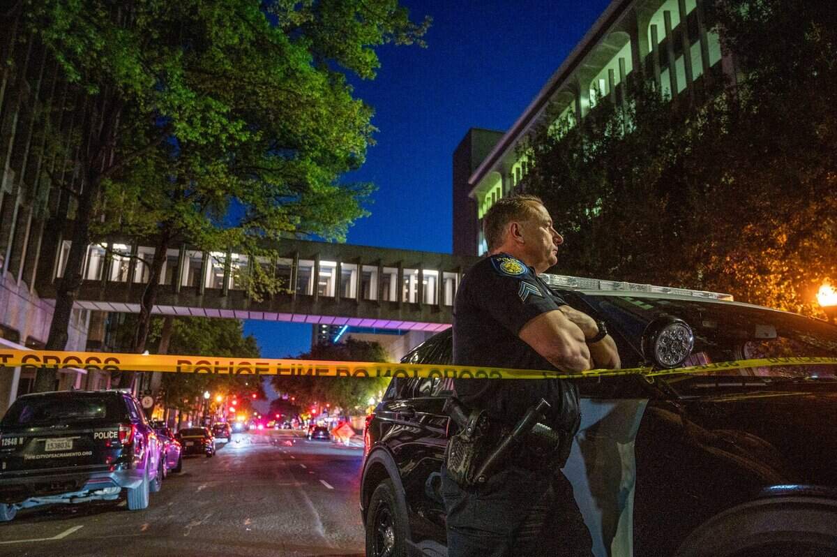A Sacramento Police officerstands watch at the scene of a mass shooting at 10th and L streets in downtown Sacramento on Sunday, April 3, 2022.