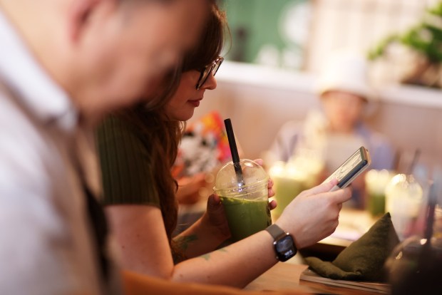 Cleo Brock, a moderator with the San Jose Silent Book Club, sips matcha and reads from a tablet at Maruwu Seicha in Campbell on Sunday, July 26, 2026. (Aric Crabb/Bay Area News Group)
