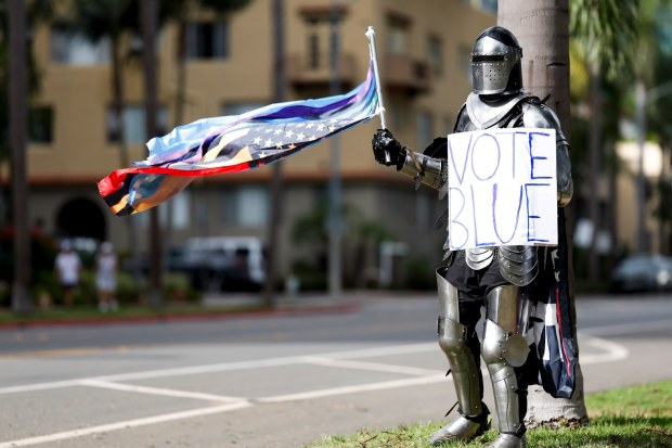 Kenneth Perry, of Escondido, waves a flag near the street during a No Kings protest at Balboa Park on Saturday, Oct. 17, 2026 in San Diego, California. (Meg McLaughlin / The San Diego Union-Tribune)