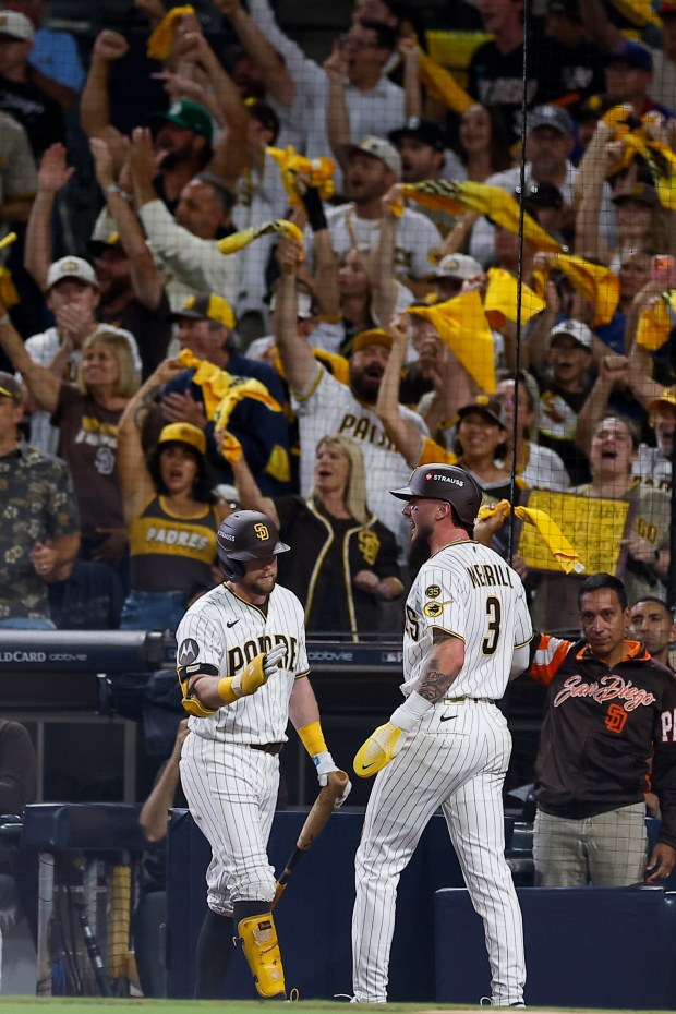 Jackson Merrill celebrates with Jake Cronenworth after scoring a run during Wednesday's win over the Chicago Cubs in Game 2 of the National League Division Series. (Meg McLaughlin / The San Diego Union-Tribune)