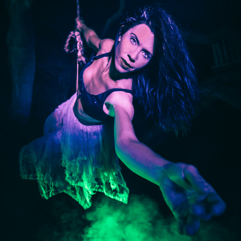 A woman leans into the camera, hanging down from a wire.