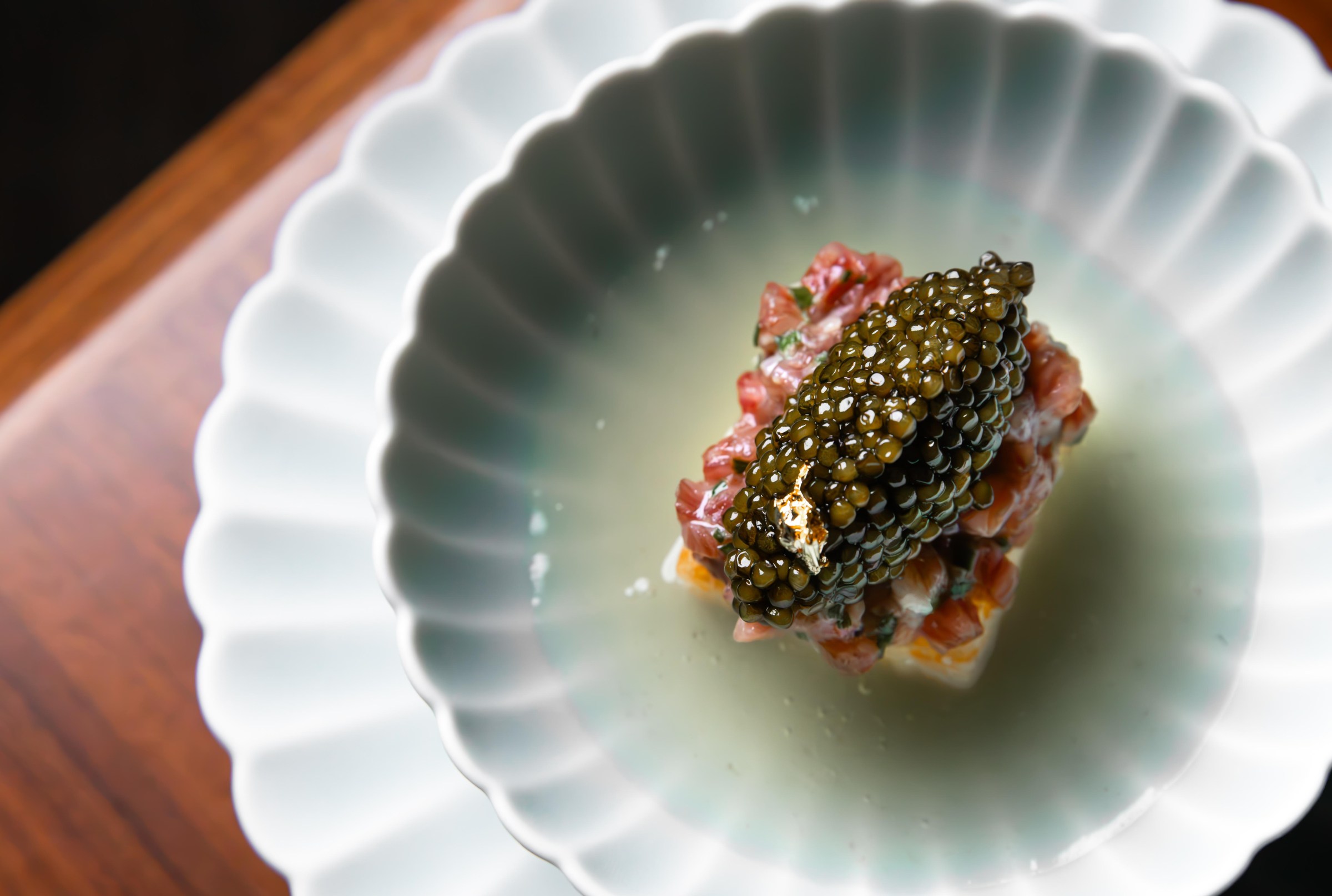 A bowl featuring a bite of food with caviar, in a clear broth, at Shinka in San Francisco.