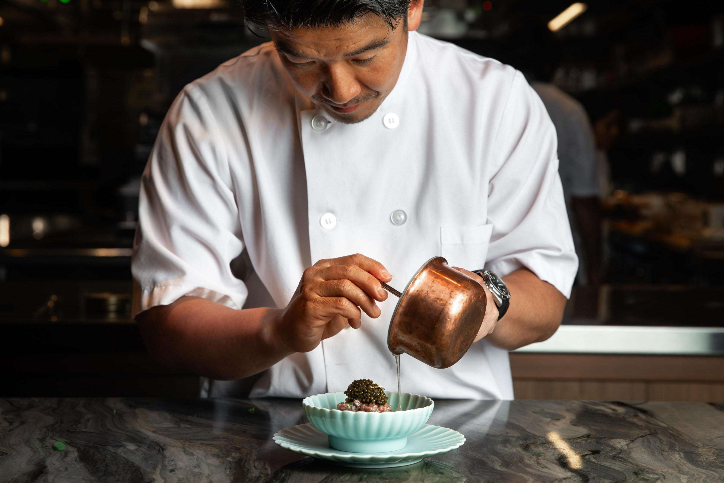 Chef Fumio Yonezawa of Shinka in San Francisco pours a broth into a bowl featuring a bite with caviar.