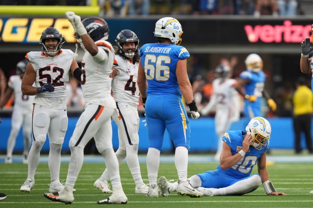 Los Angeles Chargers quarterback Justin Herbert, right, sits on the...