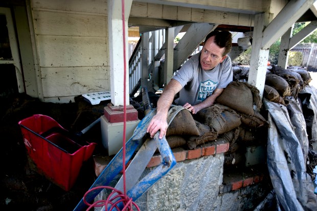 Eric Heckman works on draining the flooded back yard of their house that rests near the bank of the Coyote Creek in San Jose, Calif. on Wednesday, Feb. 22, 2017. (LiPo Ching/Bay Area News Group)