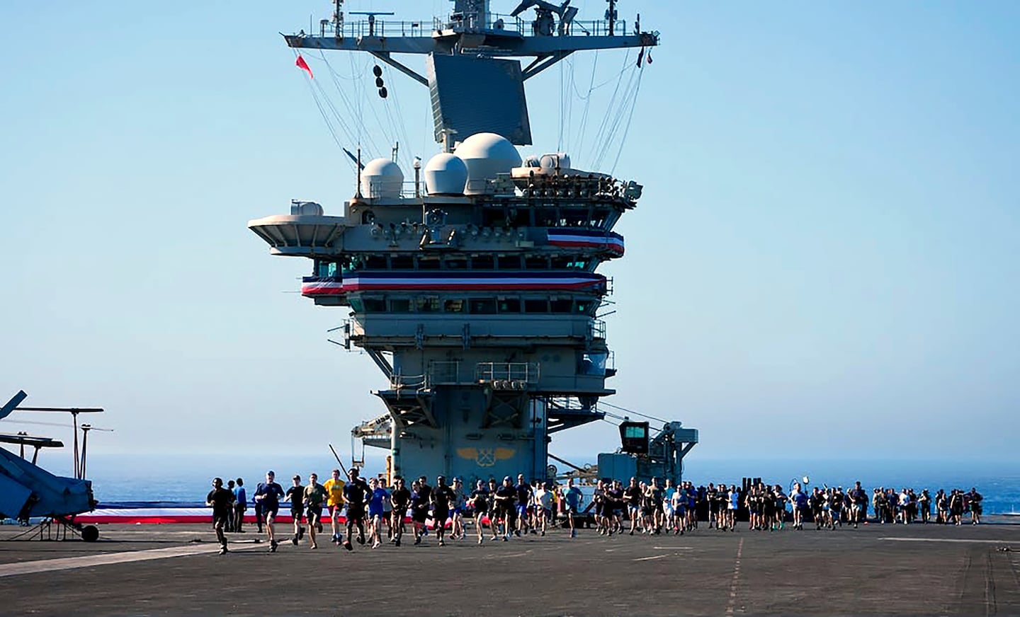 Crew members take part in a traditional 5K run, called the Ship to Shore 5K Scramble, doing several laps on the flight deck of the US Abraham Lincoln's on Oct. 7, 2026, on their return to its home port at Naval Air Station North Island in San Diego, Calif.