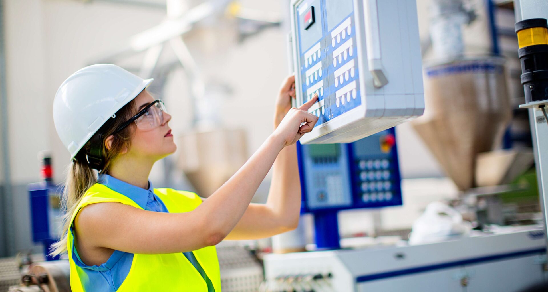 female worker in PPE operating an industrial control unit