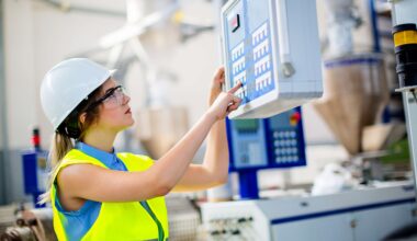 female worker in PPE operating an industrial control unit