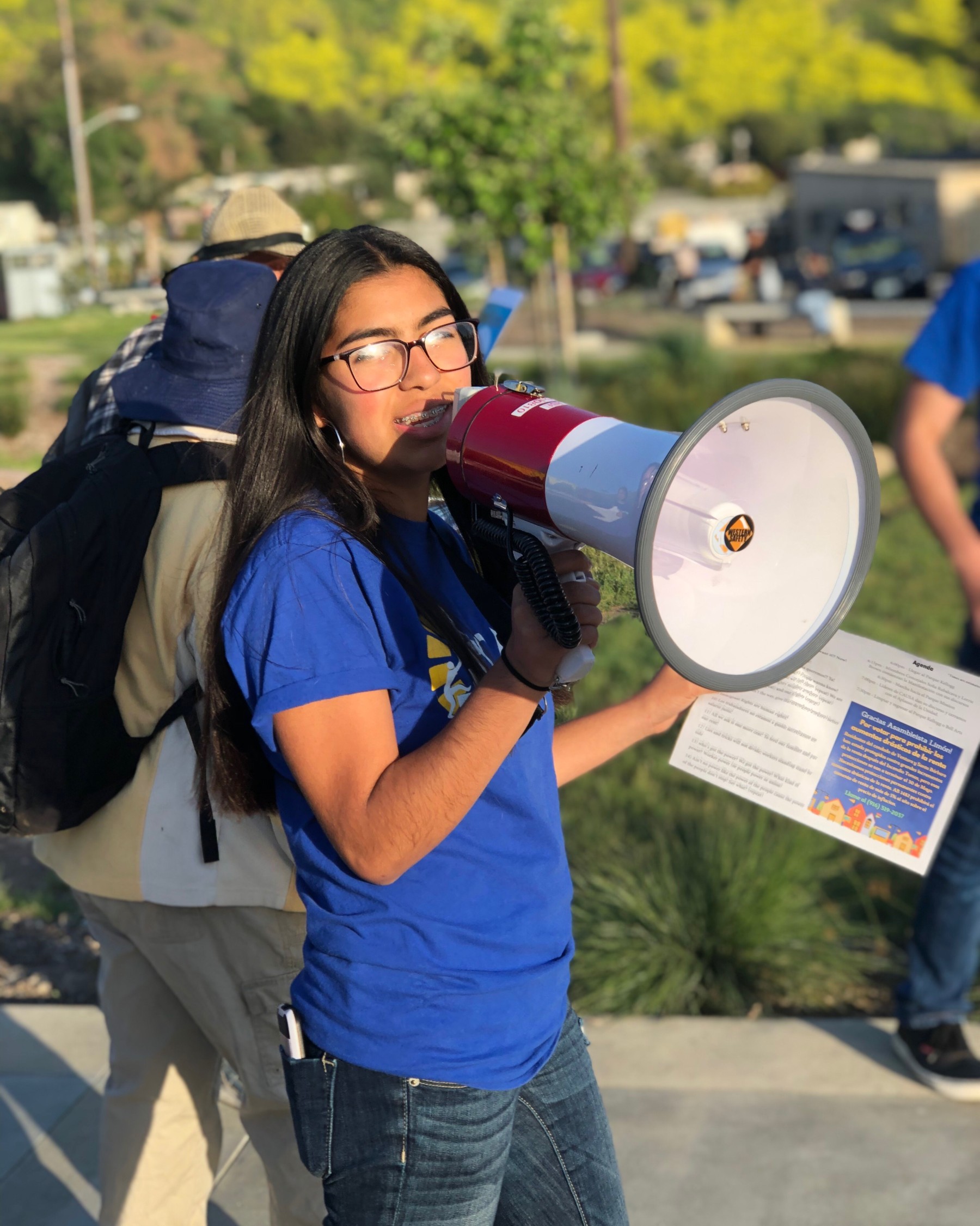 A young woman activist speaks into a bullhorn at a demonstration