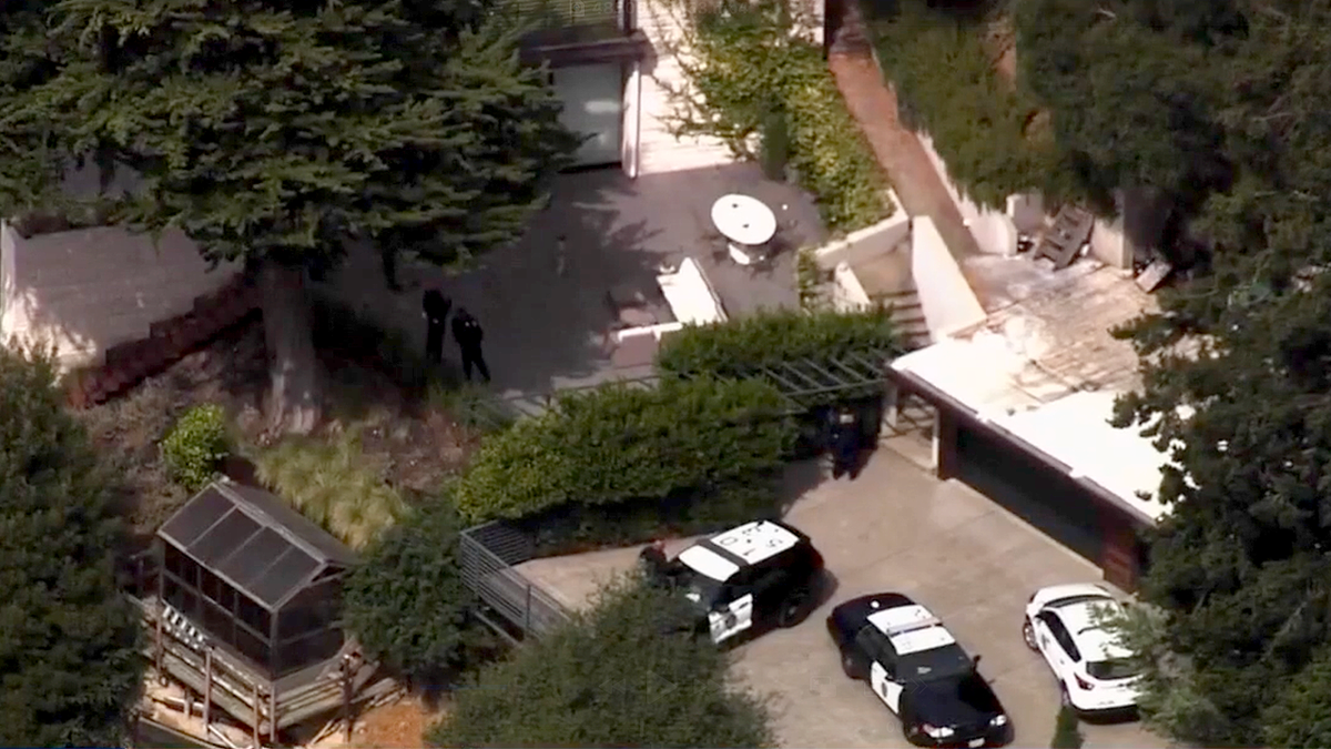 Aerial view of police vehicles and officers outside a hillside home in Oakland
