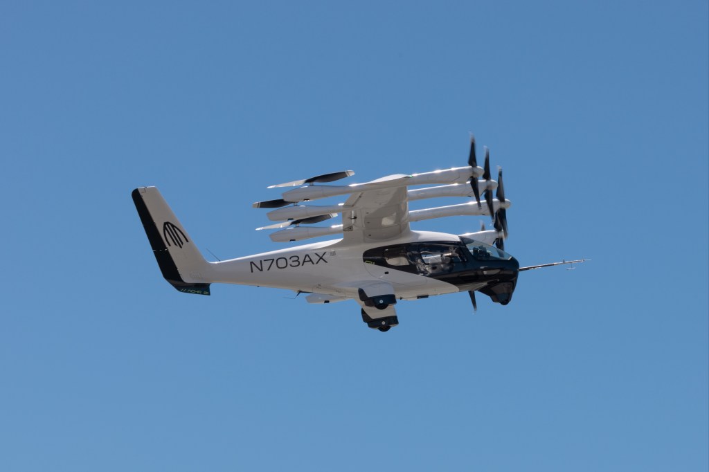 A white Archer eVTOL aircraft in flight against a clear blue sky.