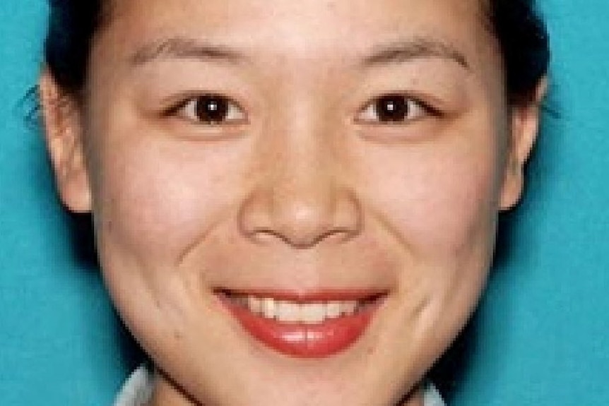 A headshot of a woman with brown eyes and long brown hair tied back, smiling.