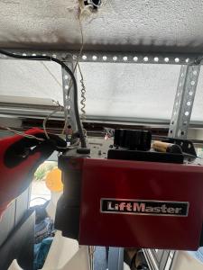 Close-up of technician inspecting electrical wiring and logic board connections during a garage door opener shortage repair in California.